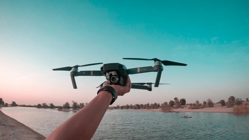 A person holds a drone over a lake in the Dubai desert, showcasing a scenic aerial view.